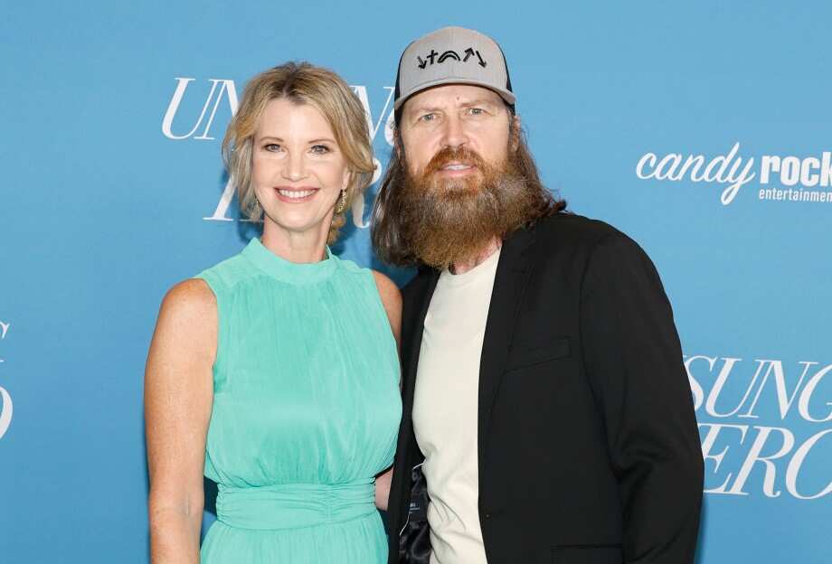 Missy Robertson in a blue dress and Jase Robertson in a white T-shirt and black jacket posing for a photo