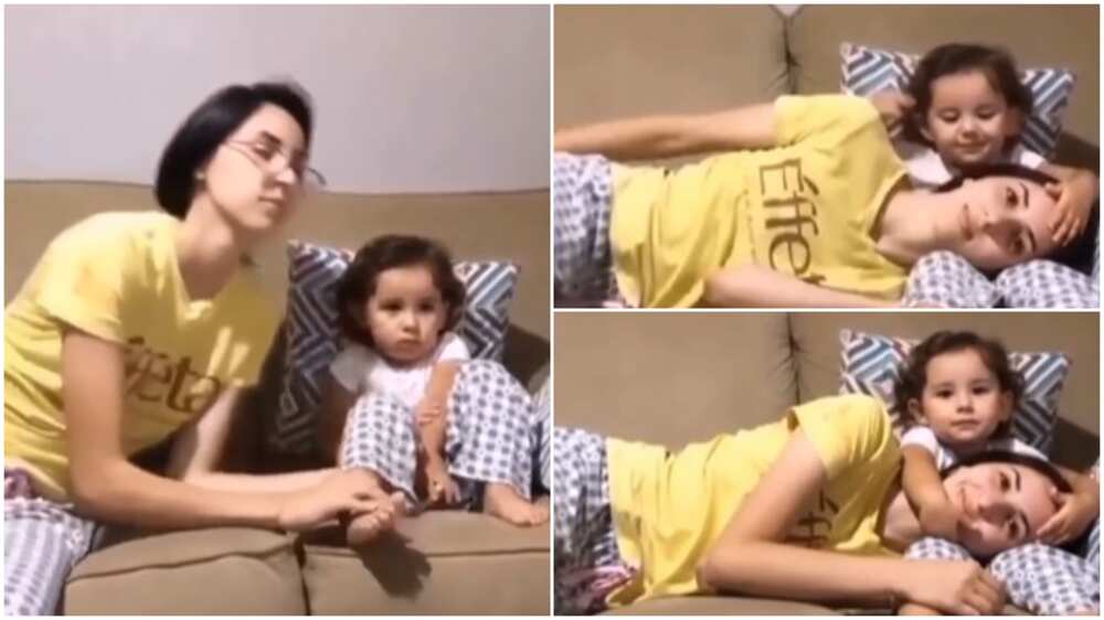 Beautiful moment mother rests on baby's legs, she pats her head in lovely way