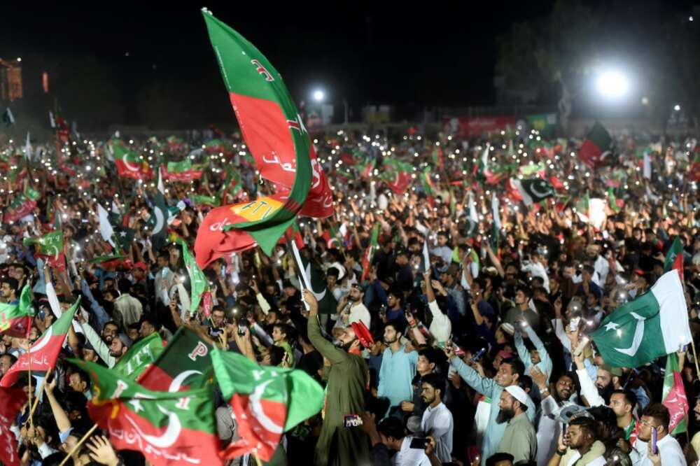 Supporters of former Pakistan prime minister Imran Khan wave flags during his speech in Karachi