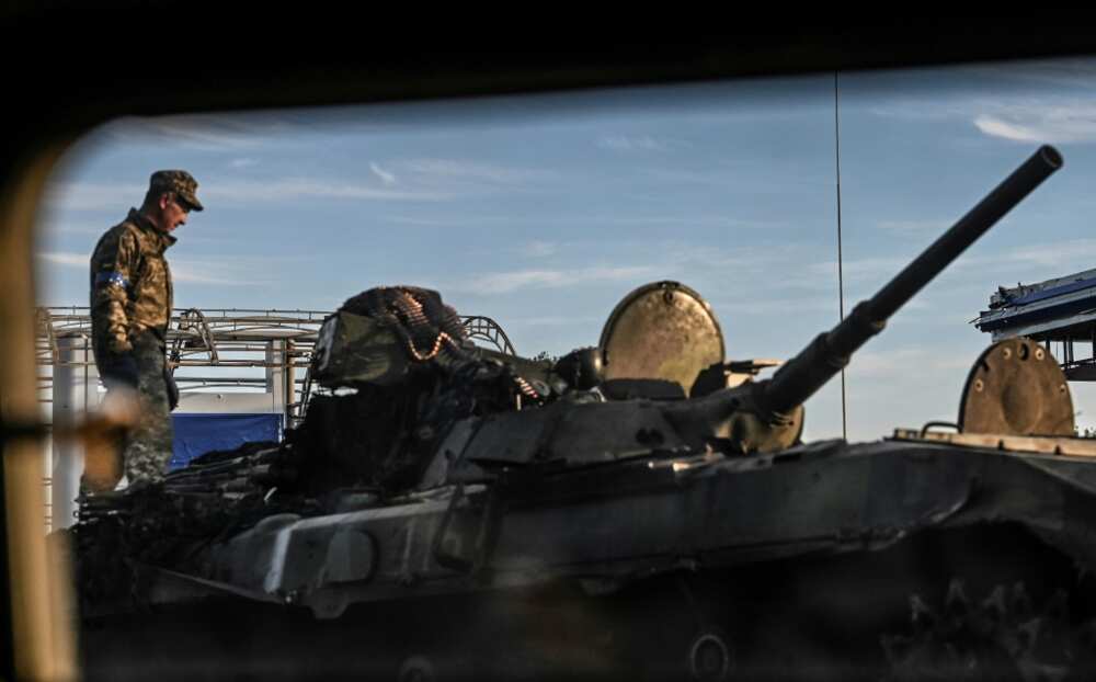 A Ukrainian fighter stands on the top of a tank in Kharkiv
