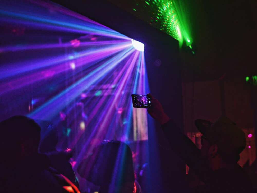 People dancing in a neon-lit nightclub to disco music
