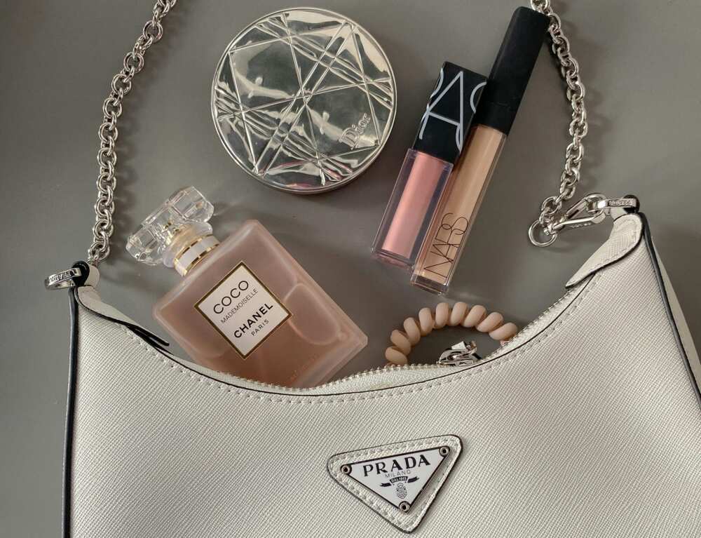 A flat lay shot of a bag with makeup and perfume