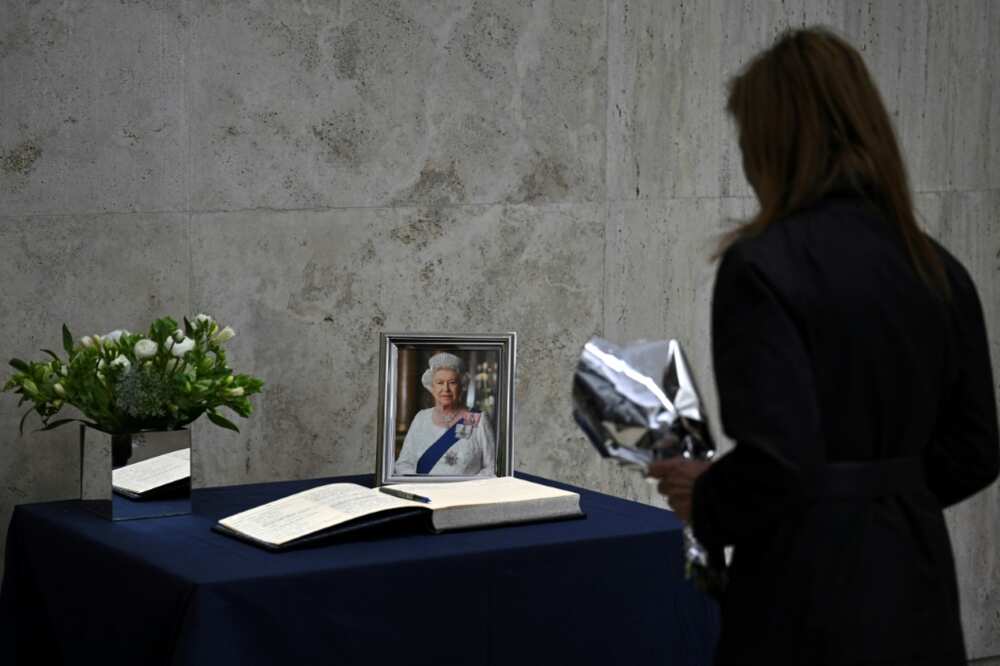Una mujer rinde homenaje a la reina Isabel II con un ramo de flores y un mensaje en el libro de condolencias de la embajada británica en Buenos Aires, el 9 de septiembre de 2022