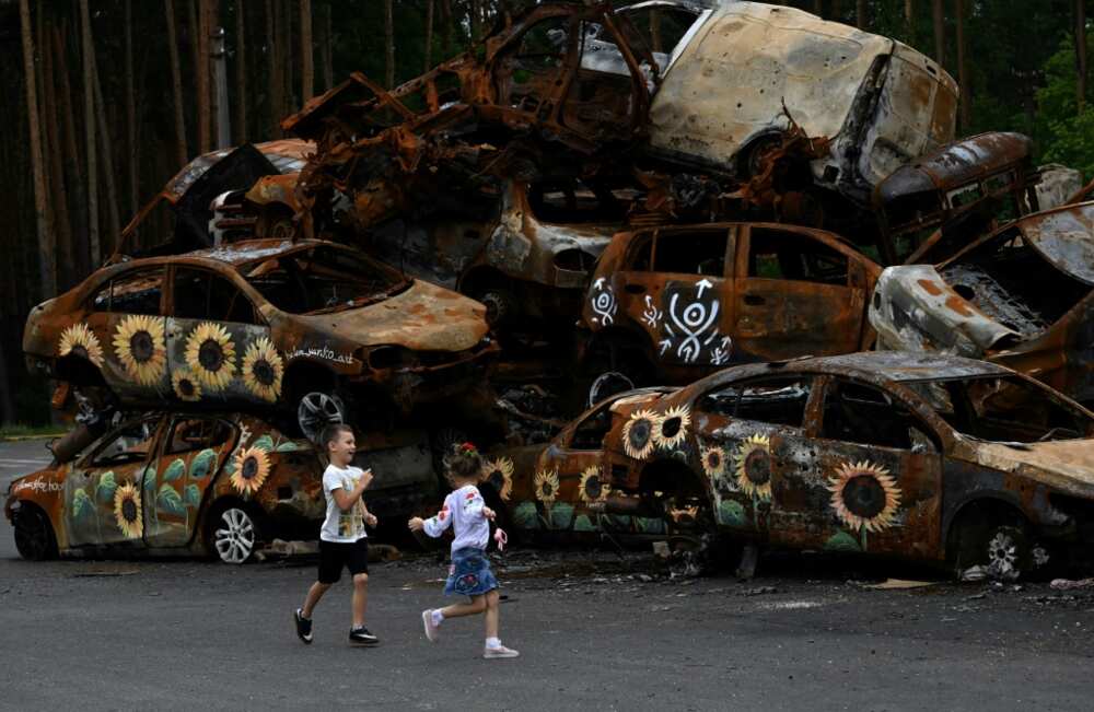 Children play at a symbolic cemetery of cars shot by Russian troops in Irpin near Kyiv