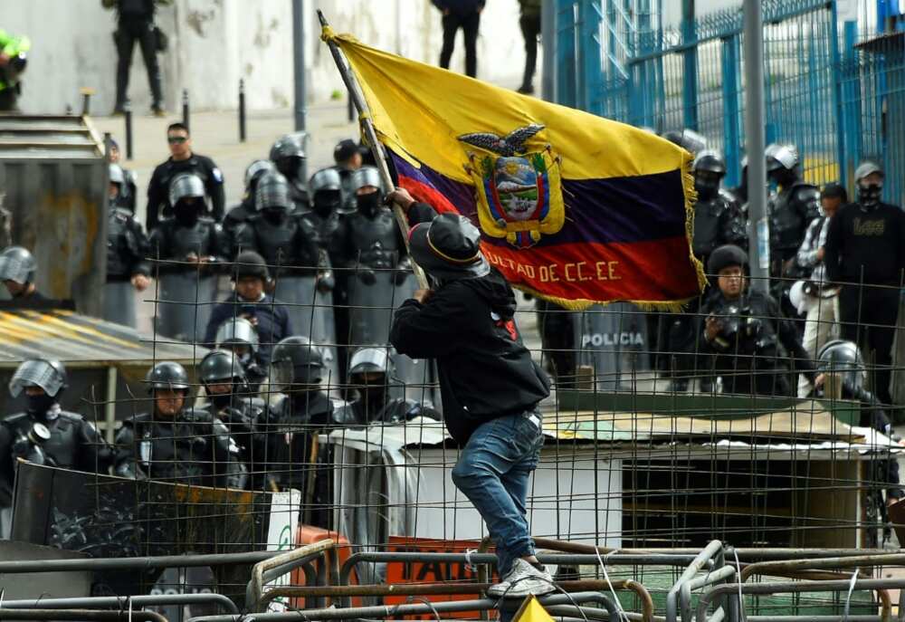 A demonstrator faces off with police officers near the National Assembly in Quito on June 25, 2022