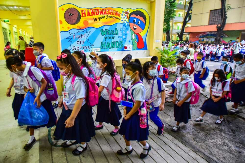 Children in masks and uniforms are returning to Pedro Guevara Elementary School in Manila, which had shut classrooms since March 2020