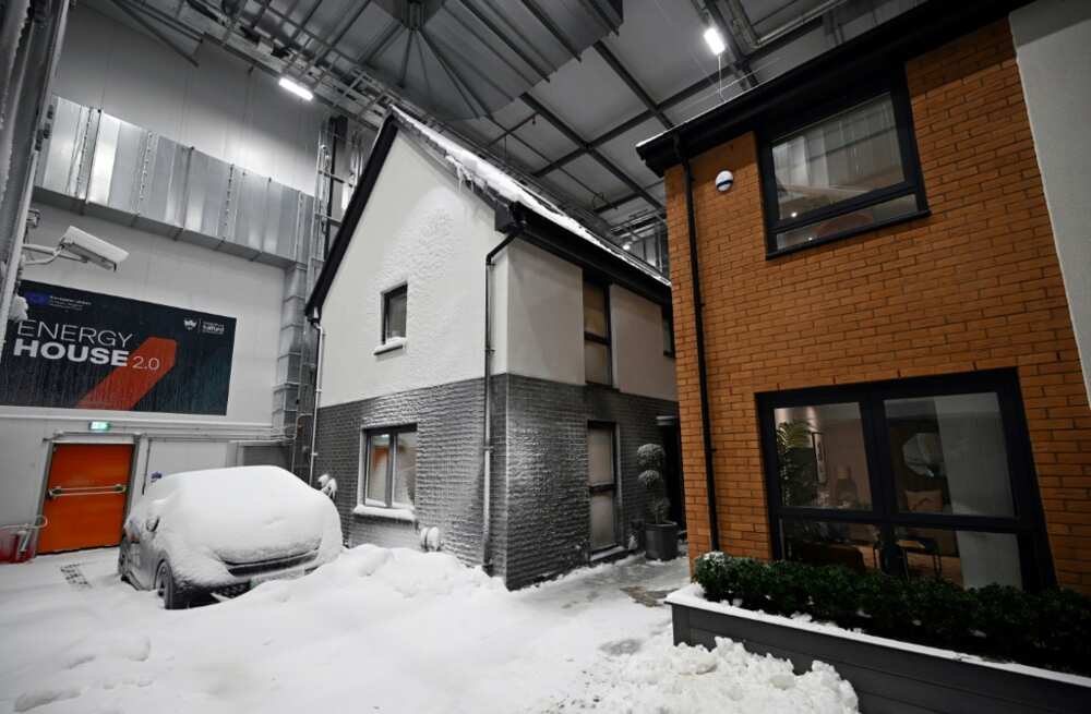 Simulated snow covers a car and the walls of one of two houses built in a lab to develop future heating solutions that will use less energy and help meet climate goals Simulated snow covers a car and the walls of one of two houses built in a lab to develop future heating solutions that will use less energy and help meet climate goals