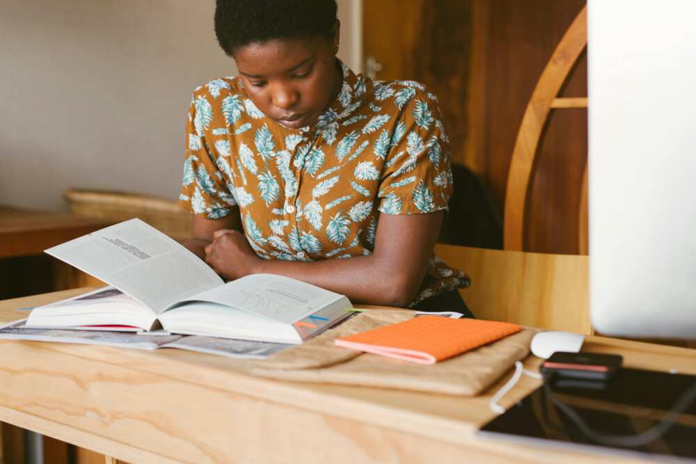 A student in a flowered top in class reading a book