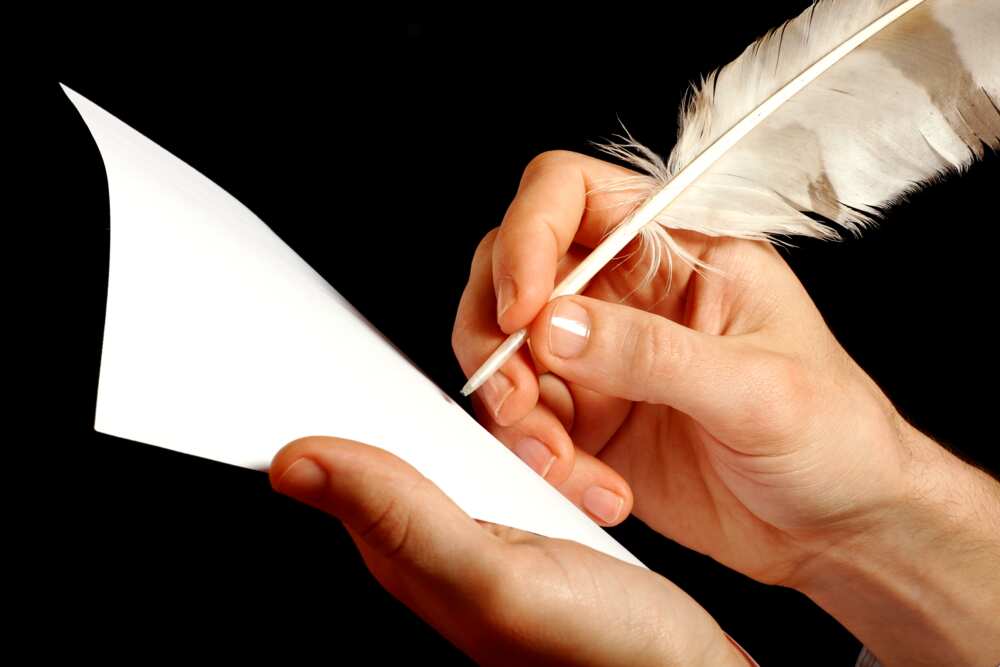 A hand writing with a feather pen