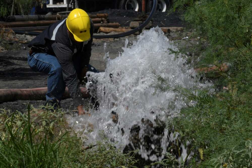 A rescuer works with a hose at a flooded mine in northern Mexico where 10 workers have been trapped for more than a week