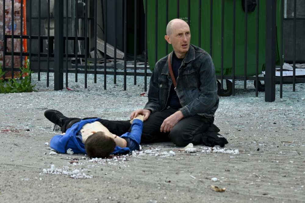 A relative kneels by the body of a teenager who died in a Russian missile strike at a bus stop in Kharkiv A relative kneels by the body of a teenager who died in a Russian missile strike at a bus stop in Kharkiv