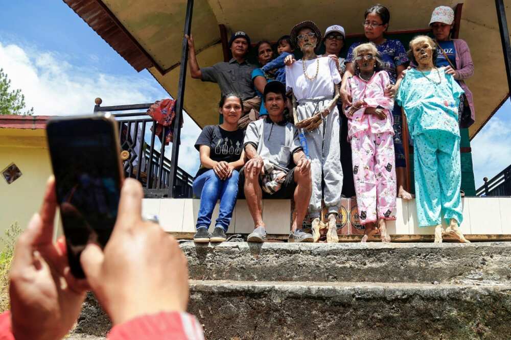 An Indonesian family poses with a dead relative as part of a ritual celebration of the afterlife