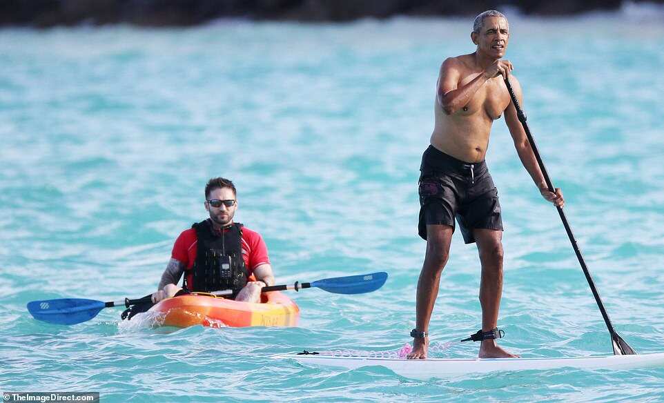 Barack Obama goes paddleboarding shirtless in Hawaii in $84 shark deterrent ankle band