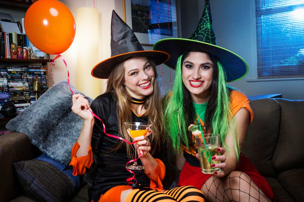 Two ladies dressed as witches on sofa