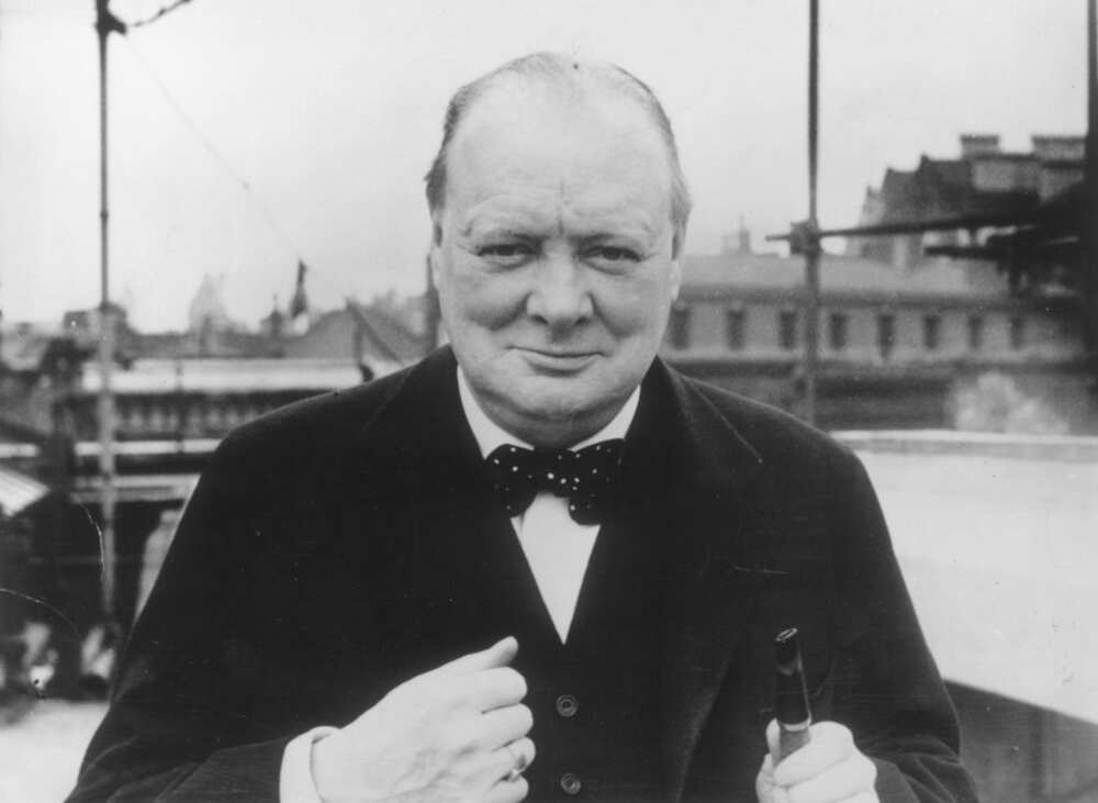 A black and white photo of Winston Churchill in a black suit and a white shirt