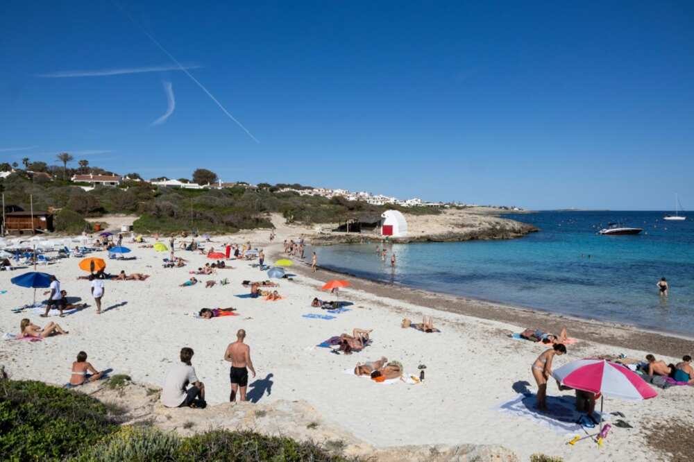 Tourists are flocking to Spain in record numbers, such as these seen sunbathing on the island of Menorca, giving the economy a huge boost