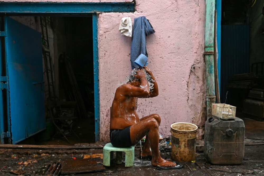 A worker bathes outside a factory in the Dharavi slums of Mumbai, where water and waste management infrastructure have not kept pace with growth