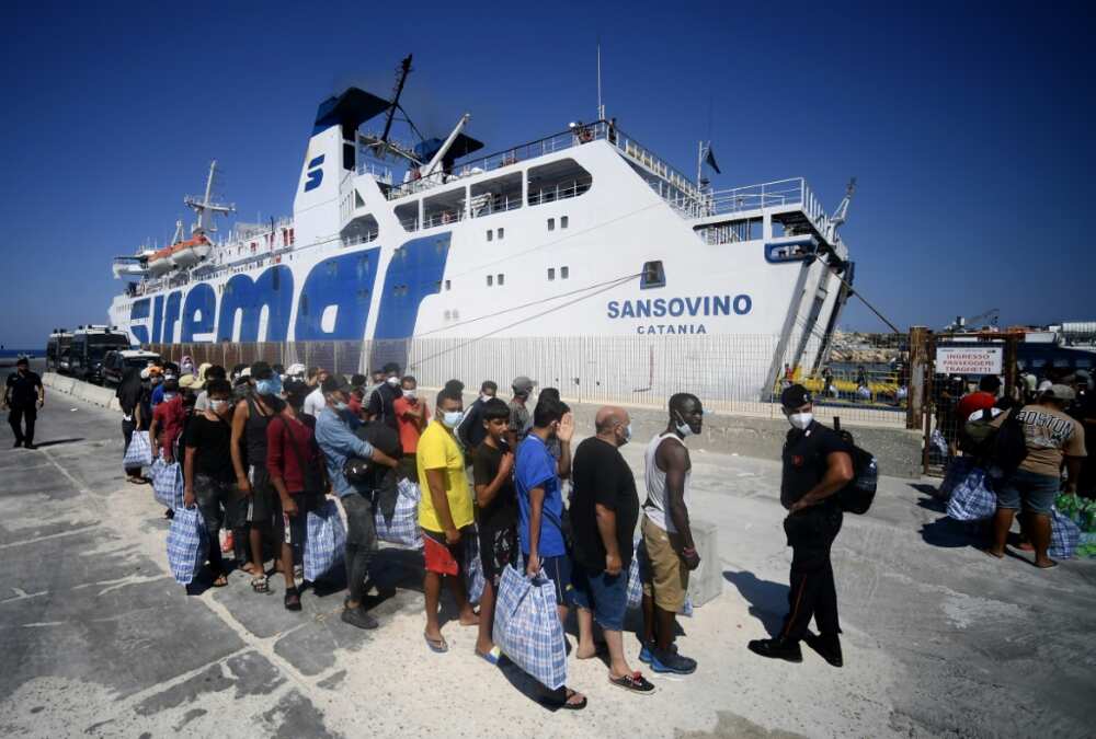 Migrants on Lampedusa wait to board a ferry boat to Sicily