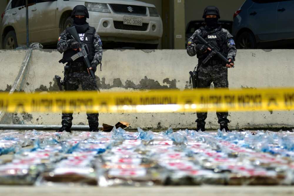 Ecuadoran anti-narcotics police stand guard next to packs of cocaine from a 3-ton shipment seized from a container of bananas in the port of Guayaquil in April 2022 -- Ecuador has become a battleground for criminal gangs involved in the drugs trade