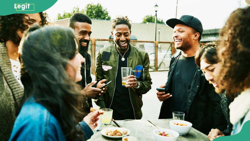 Laughing friends sharing drinks and food at an outdoor bar