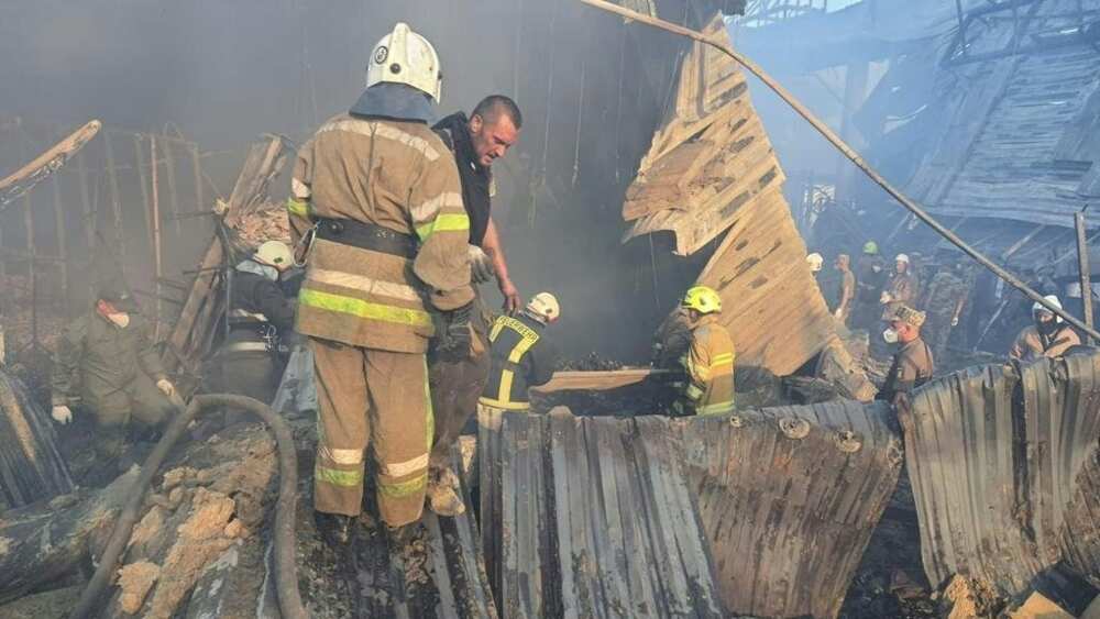 Rescue personnel work amid the smouldering remains of the mall in Kremenchuk