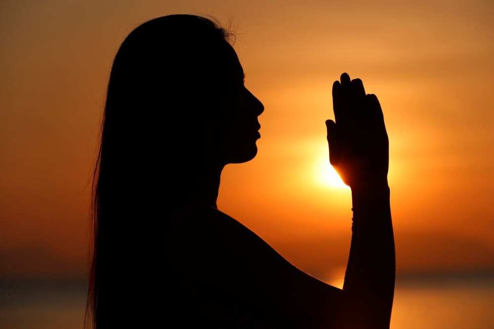 Silhouette of a woman doing a yoga pose and meditation