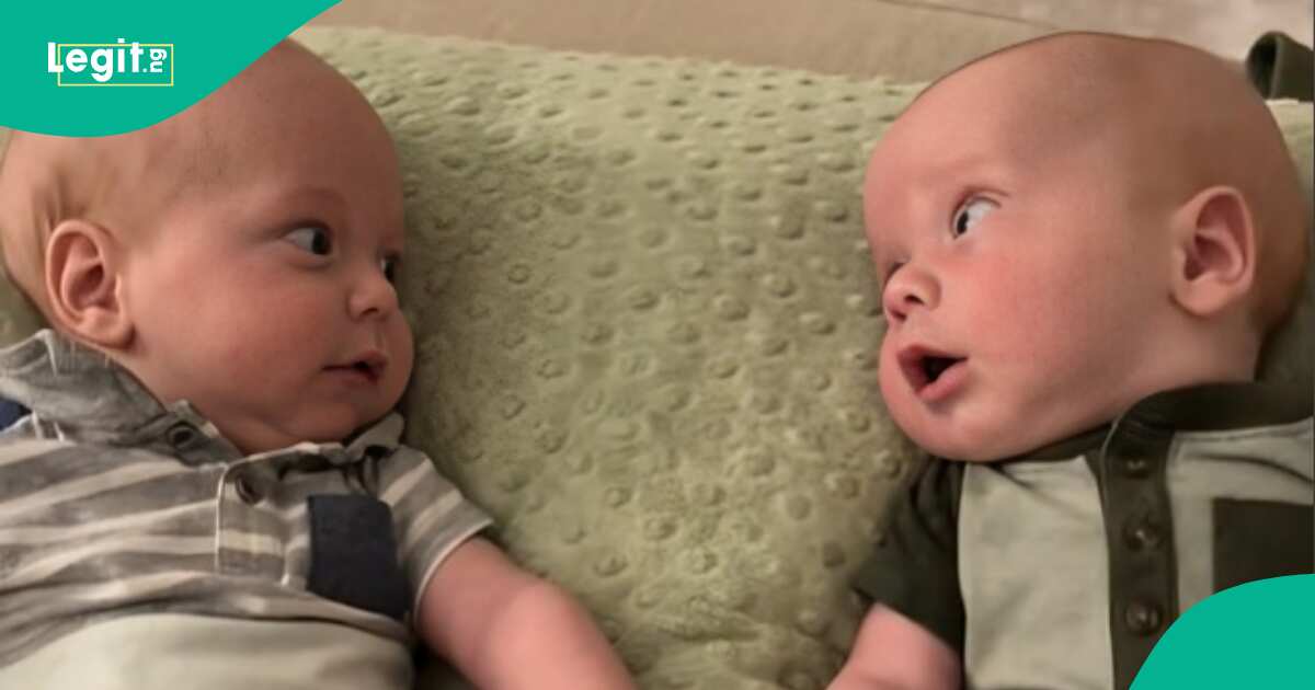 Twin babies share first smiles and eye contact, fostering hope for a lifelong bond, mother dreams their friendship will flourish into deep connection