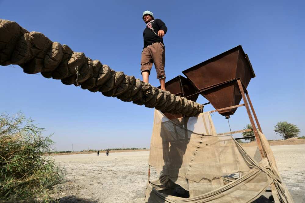 A man walks on a makeshift bridge over what is now a dry fish farm in the village of Al-Bu Mustafa