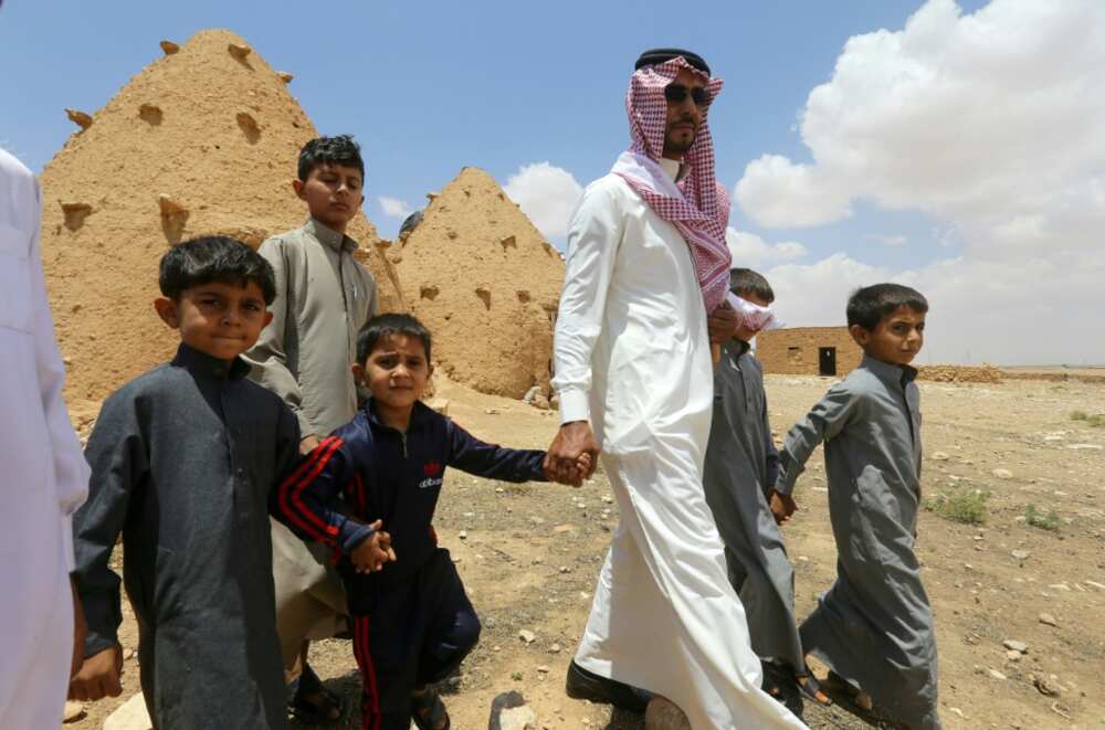 Abdulaziz al-Oqab walks with with his nephews who were orphaned when a landmine exploded under a pick-up truck, claiming the lives of 21 family members