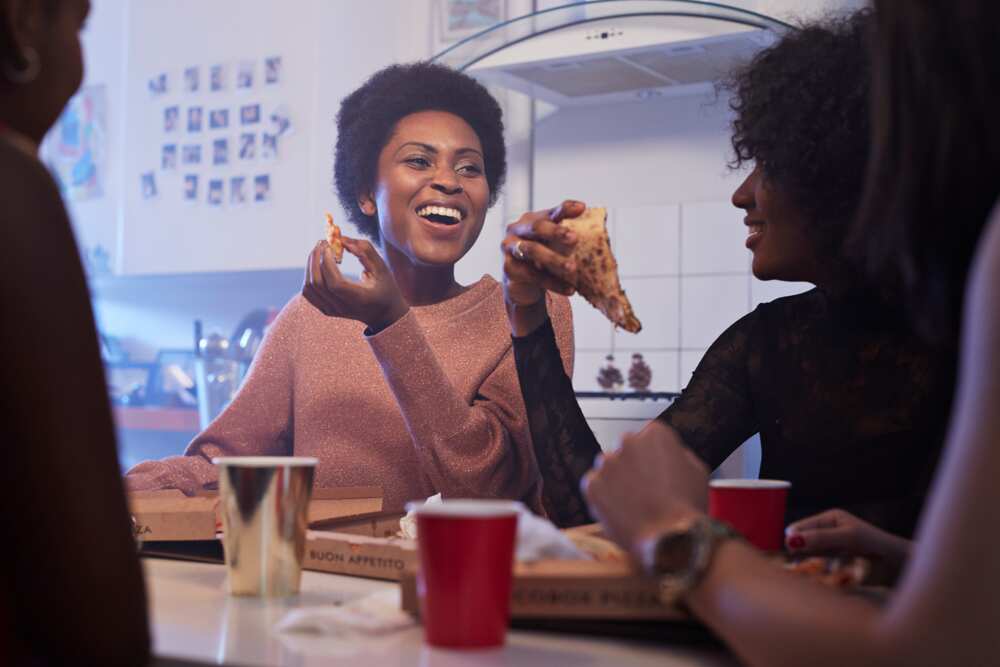 Young women eating pizza in the kitchen
