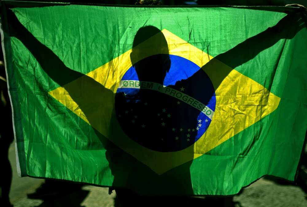Supporters of Brazilian President Jair Bolsonaro embrace the national flag as a symbol of their support for him