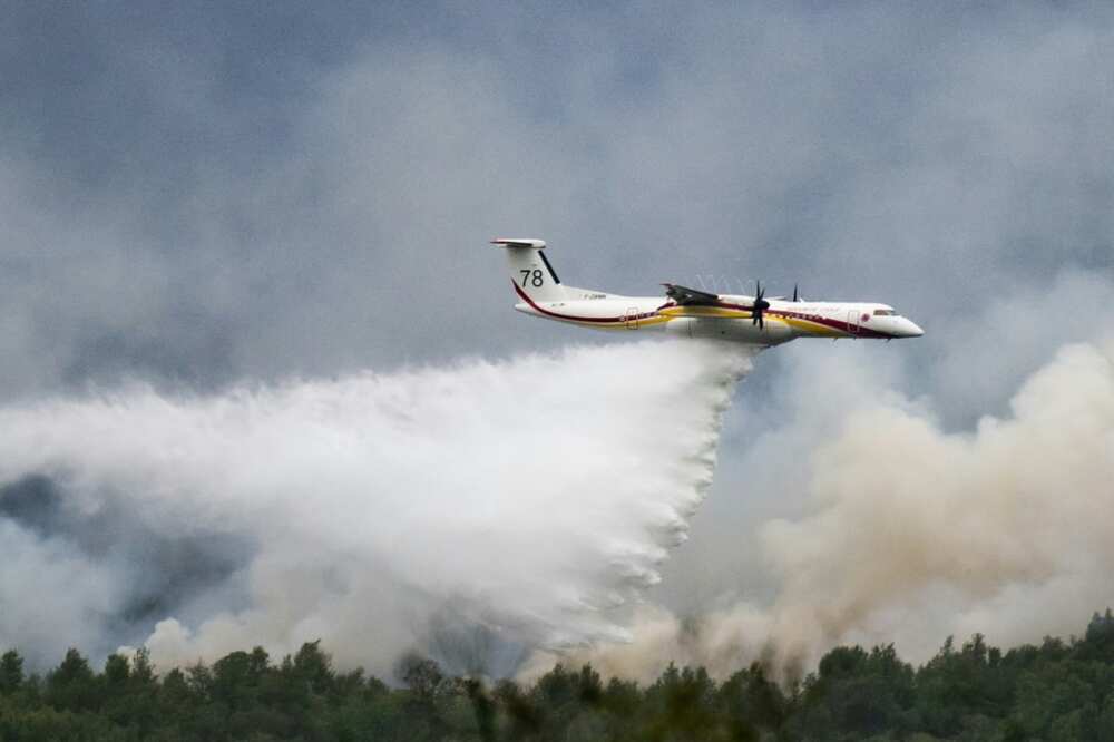 A De Havilland Canada Dash 8-400 MR aircraft drops water over a wildfire raging in the Monts d'Arree, near Brennilis, Brittany.