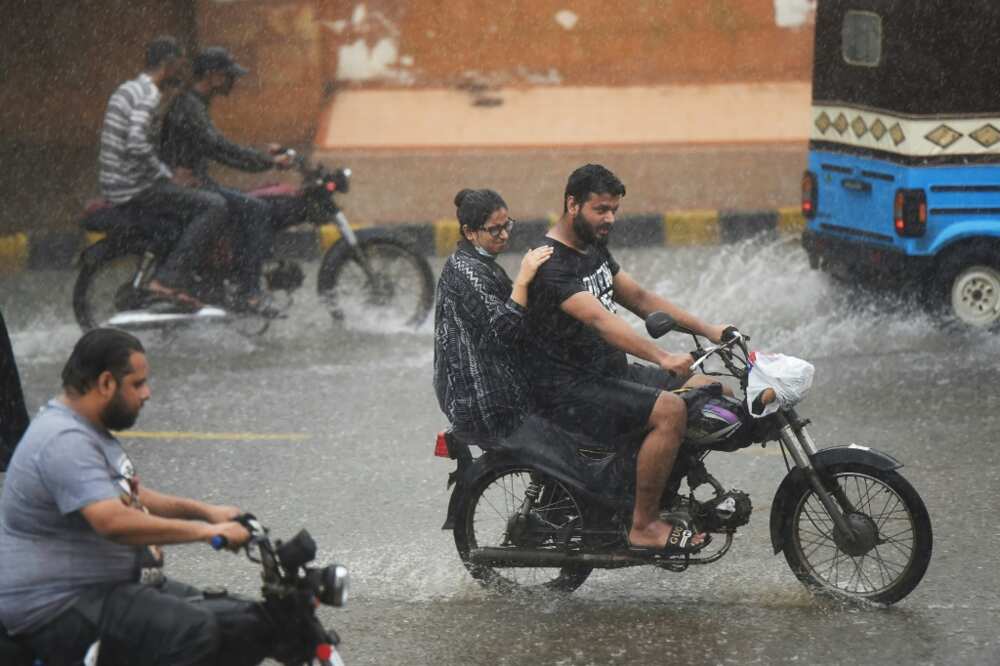 Commuters ride motorbikes along a street during a monsoon rains in Karachi