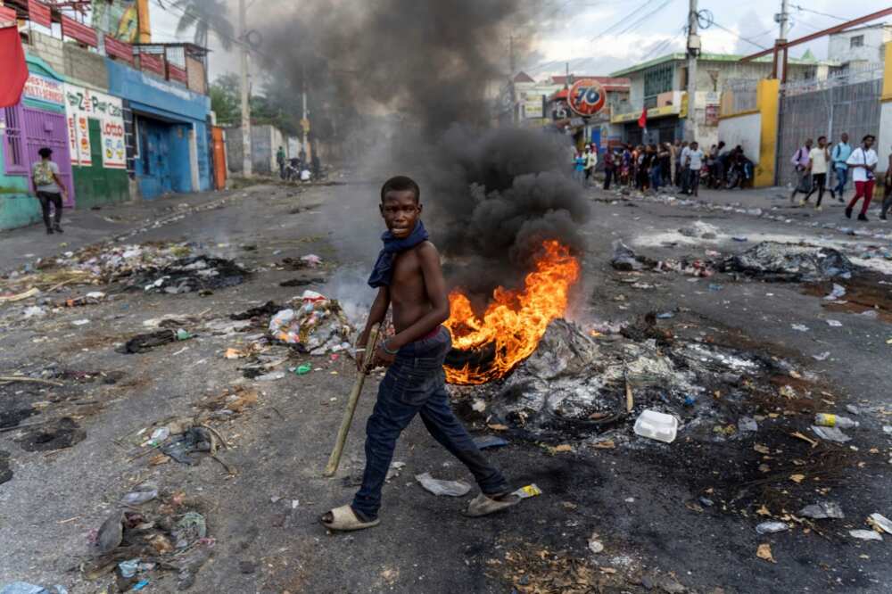 A mans walks past a burning barricade during a protest against Haitian Prime Minister Ariel Henry in Port-au-Prince on October 10, 2022
