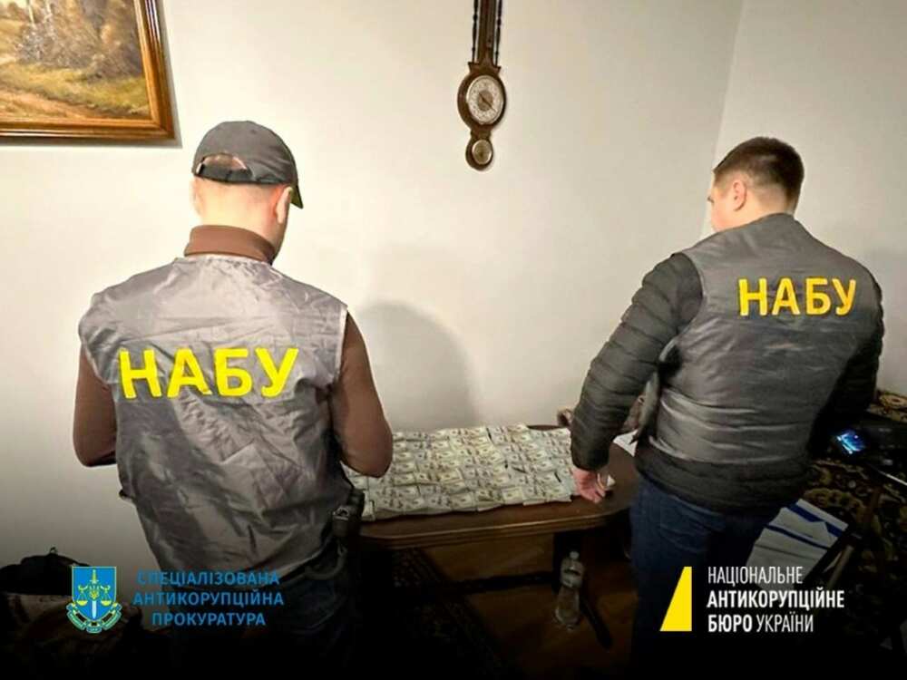 A handout photograph by the National Anti-Corruption Bureau of Ukraine shows NABU staff members next to seized money
