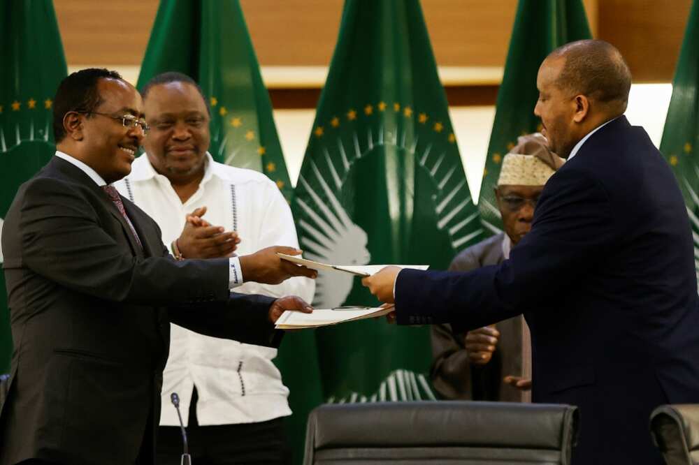 Ethiopian government representative Redwan Hussien Rameto, left, and Tigrayan rebel spokesman Getachew Reda, right, exchange documents after signing the agreement in Pretoria