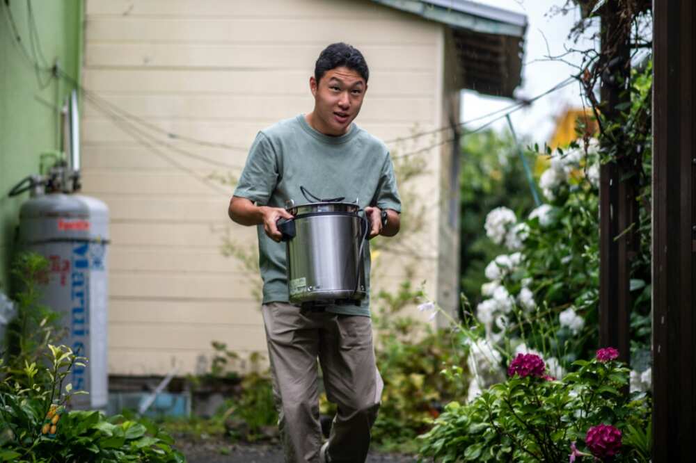 Koichi Miyatsu, 18, carries a pot from his home to a church as part of a monthly charity event for underprivileged children