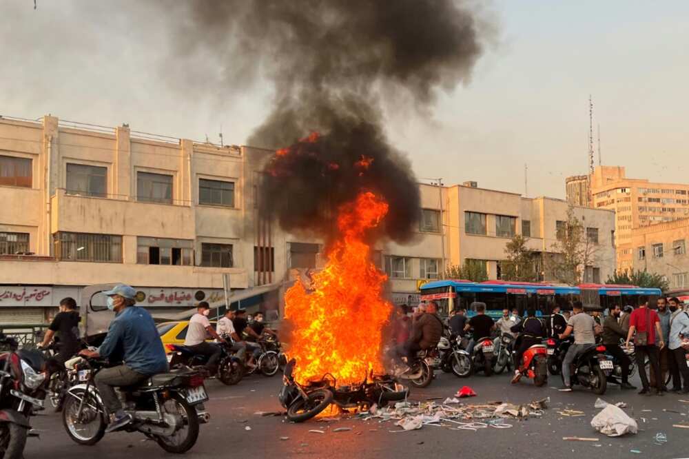 A picture obtained by AFP outside Iran shows people gathering next to a burning motorcycle in Tehran