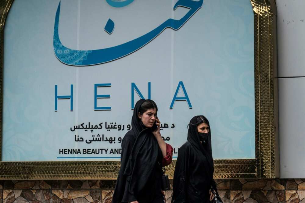 Women walk past a beauty salon in the Shahr-e-Naw area of Kabul ahead ahead of the order for beauty parlours across the country to shut permanently
