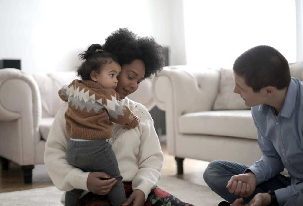 Child hugs her mother while staring at her father