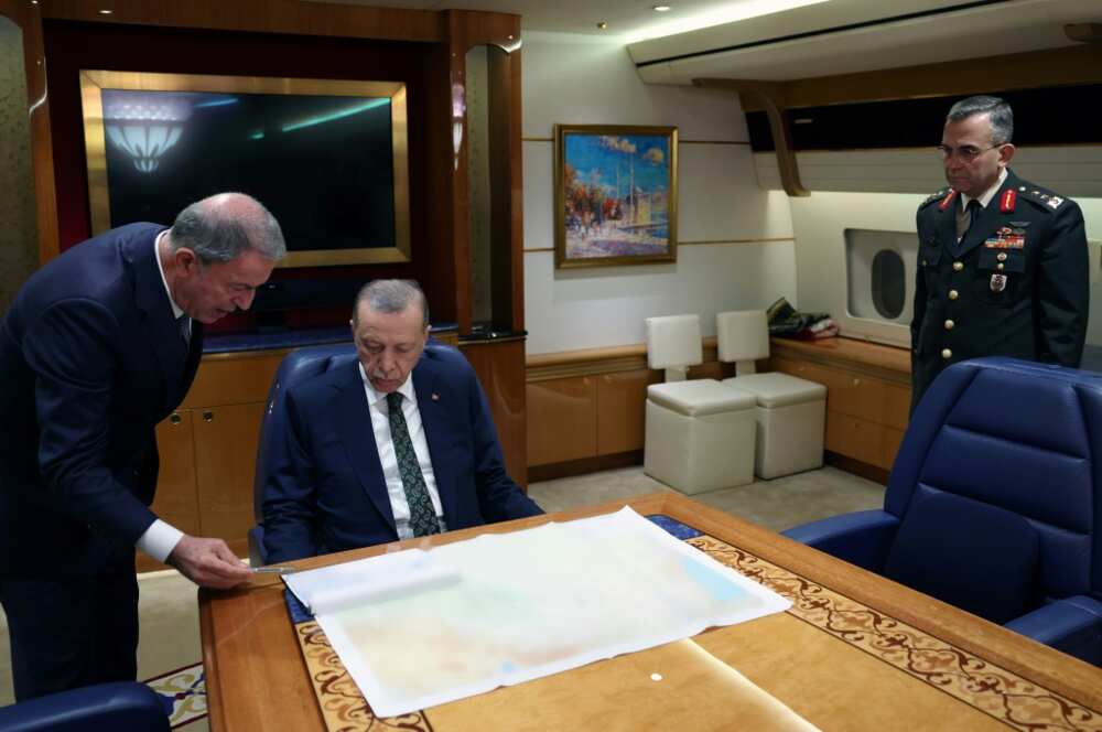 Turkey's President Recep Tayyip Erdogan (C) speaks with National Defence Minister Hulusi Akar (L) aboard the presidential aircraft.