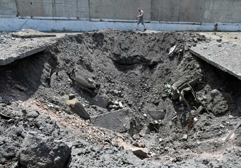 A man walks past a crater after a Russian rocket struck an industrial zone of Kharkiv on June 30, 2022