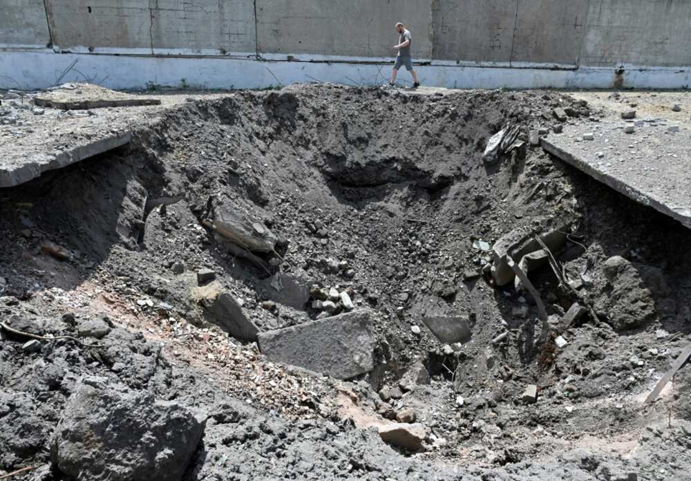 A man walks past a crater after a Russian rocket struck an industrial zone of Kharkiv on June 30, 2022 A man walks past a crater after a Russian rocket struck an industrial zone of Kharkiv on June 30, 2022