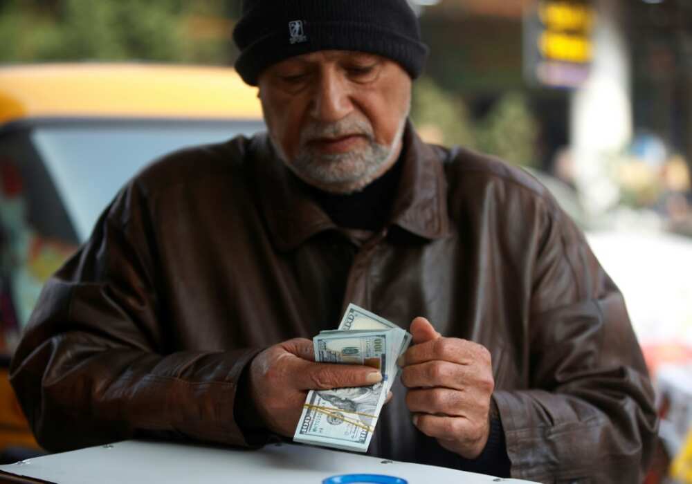 A man counts US dollar banknotes in a Baghdad market on December 27, 2022 as the value of Iraqi dinar against US dollar drops further.