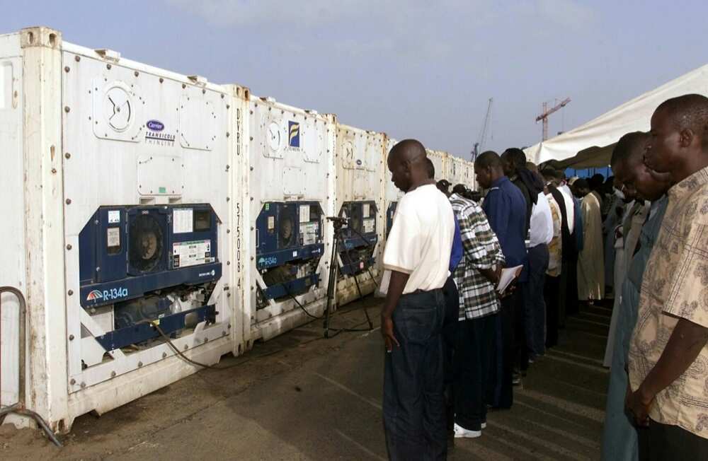 Mourners gather by containers at Dakar port holding victims after the disaster
