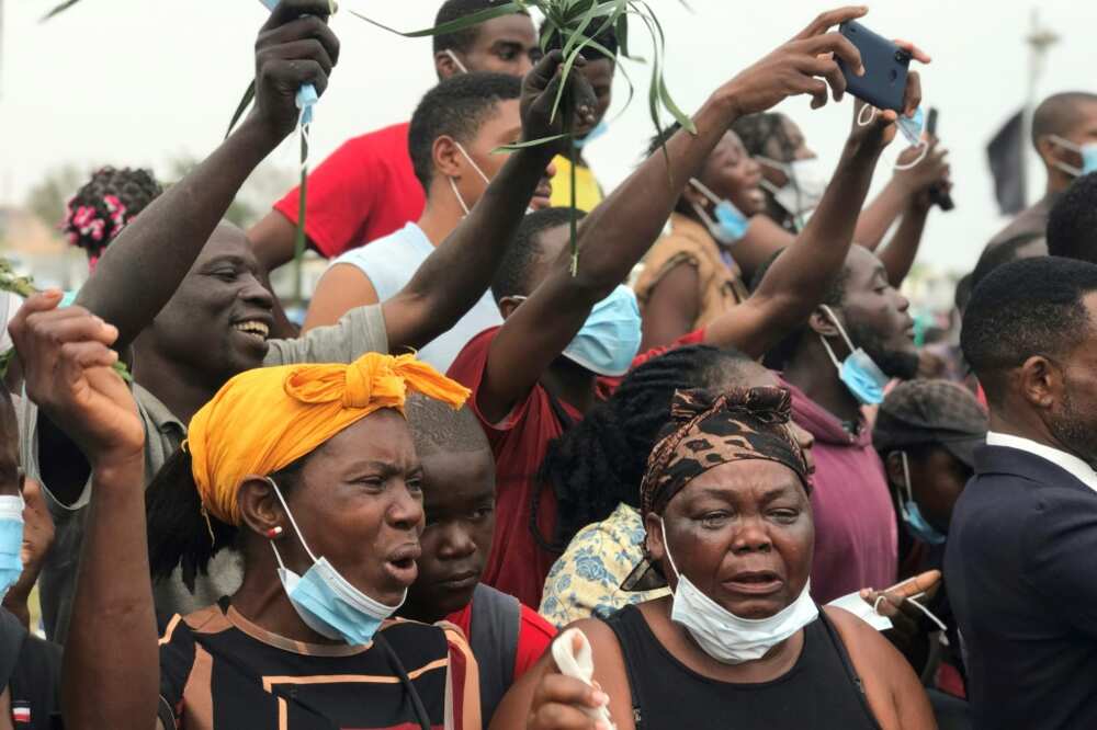 Mourners react as the cortege carrying the remains of the former president arrives at the Praca da Republica in Luanda