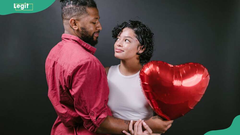 Couple looking at each other holding a red heart-shaped balloon