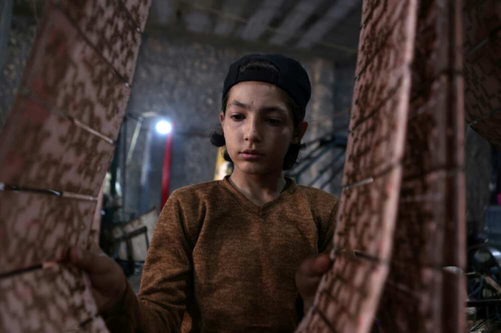 A child worker sorts through mats and rugs made from recycled plastic at a factory in Sarmada
