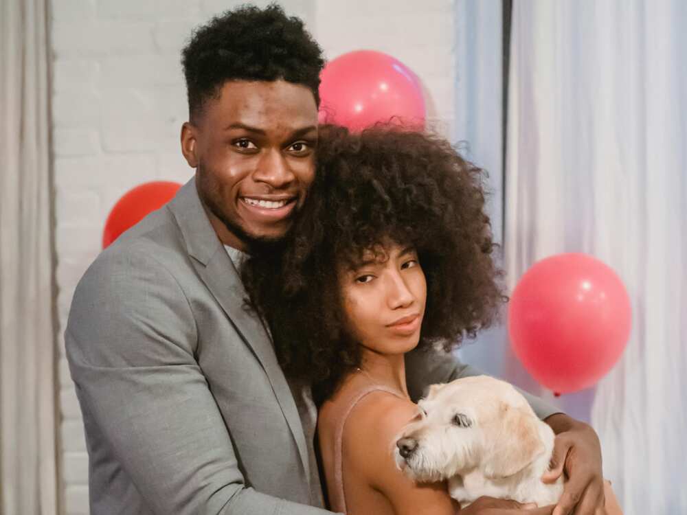 A couple holding a cute dog while standing in decorated room