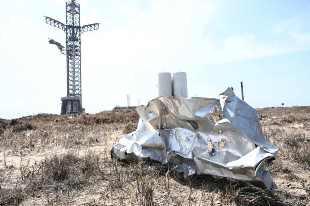 A chunk of twisted metal lies on the ground near the Starship's launch site